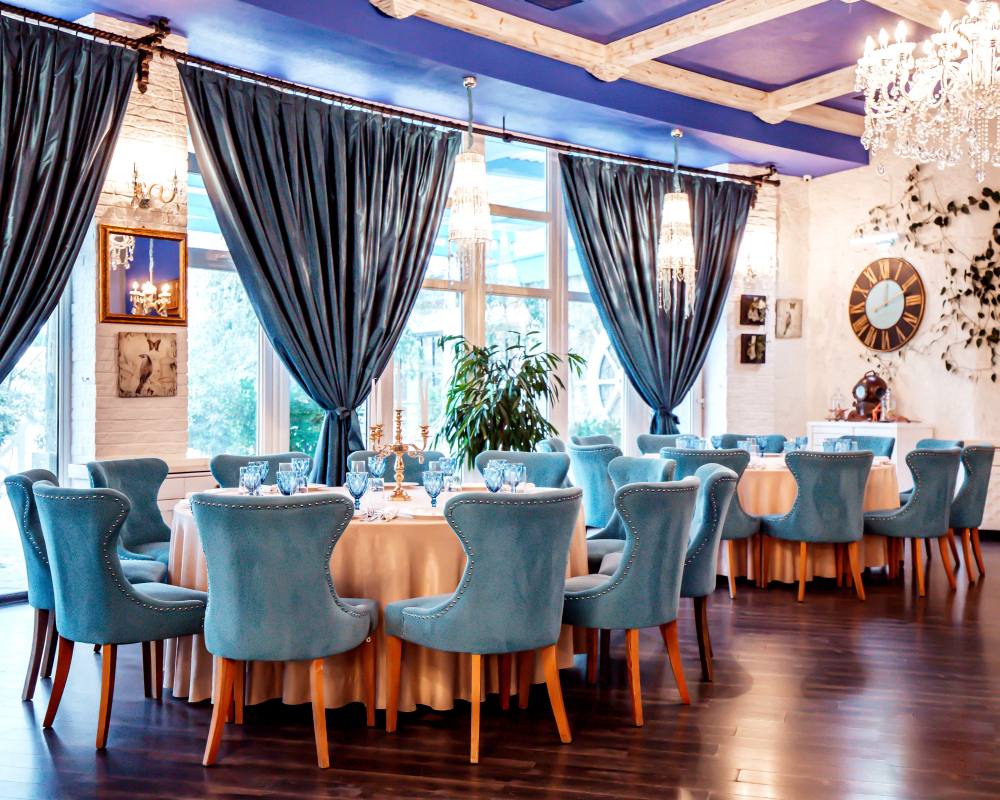 Salle de restaurant avec des chaises bleues et des rideaux