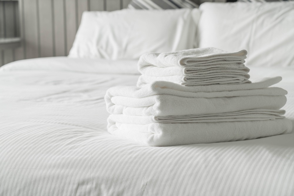 Pile de linges blancs sur un lit au drap blanc et aux taies d'oreillers blanches